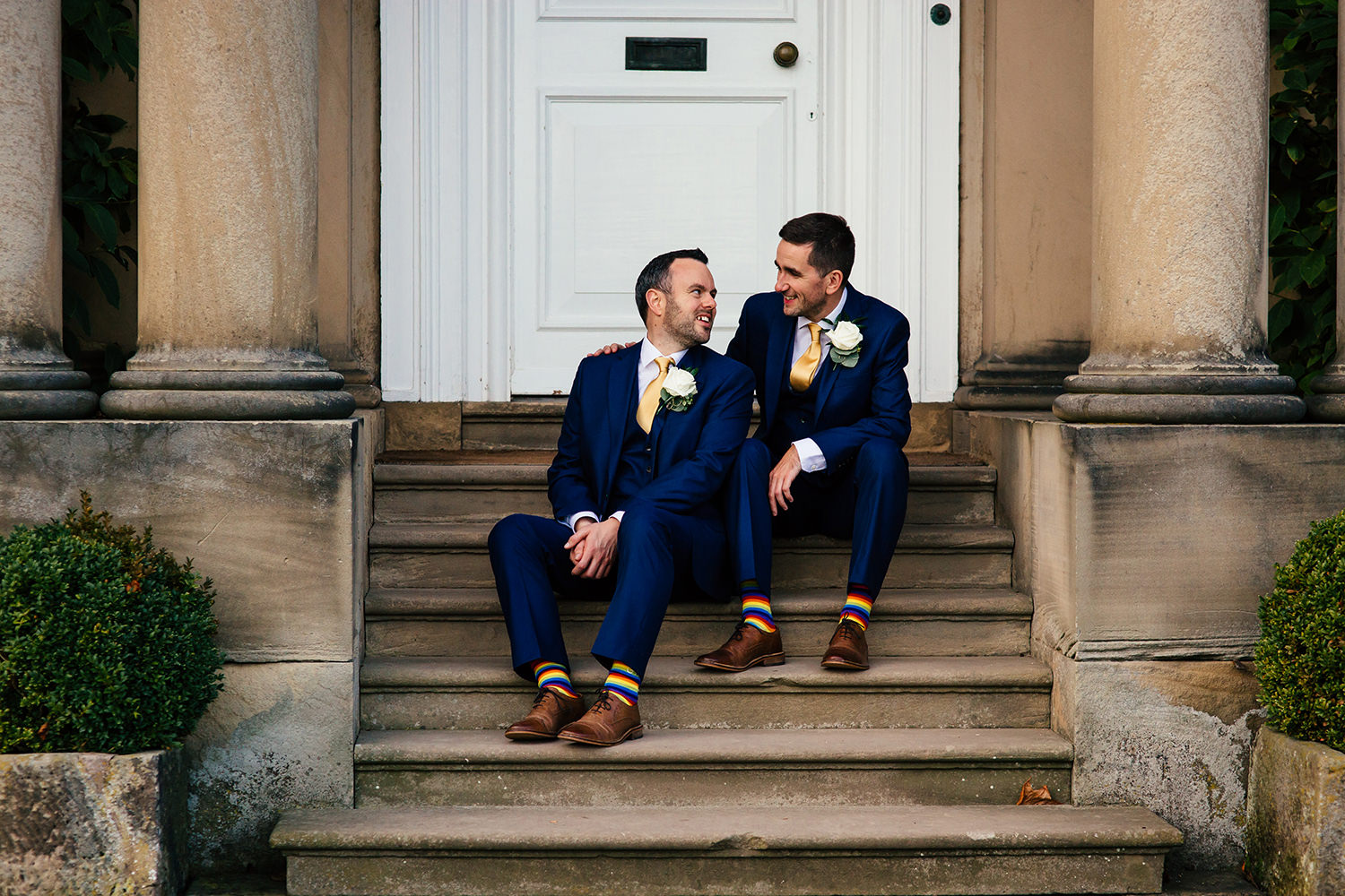 LGBTQ+ Wedding photograph of two men just married sitting on the steps