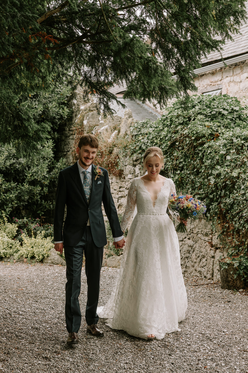 Bride and groom walking hand in hand in candid style at Faenol Fawr
