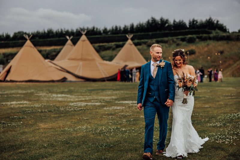 bride and groom with tipi in background