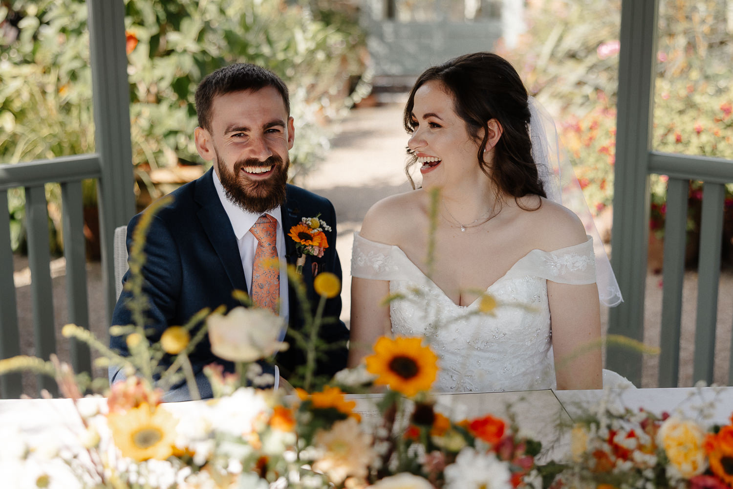 a groom and bride sitting at a table with flowers