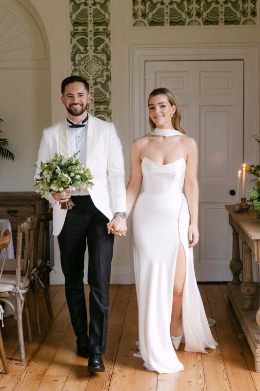 Elegant couple holding hands, wedding attire.