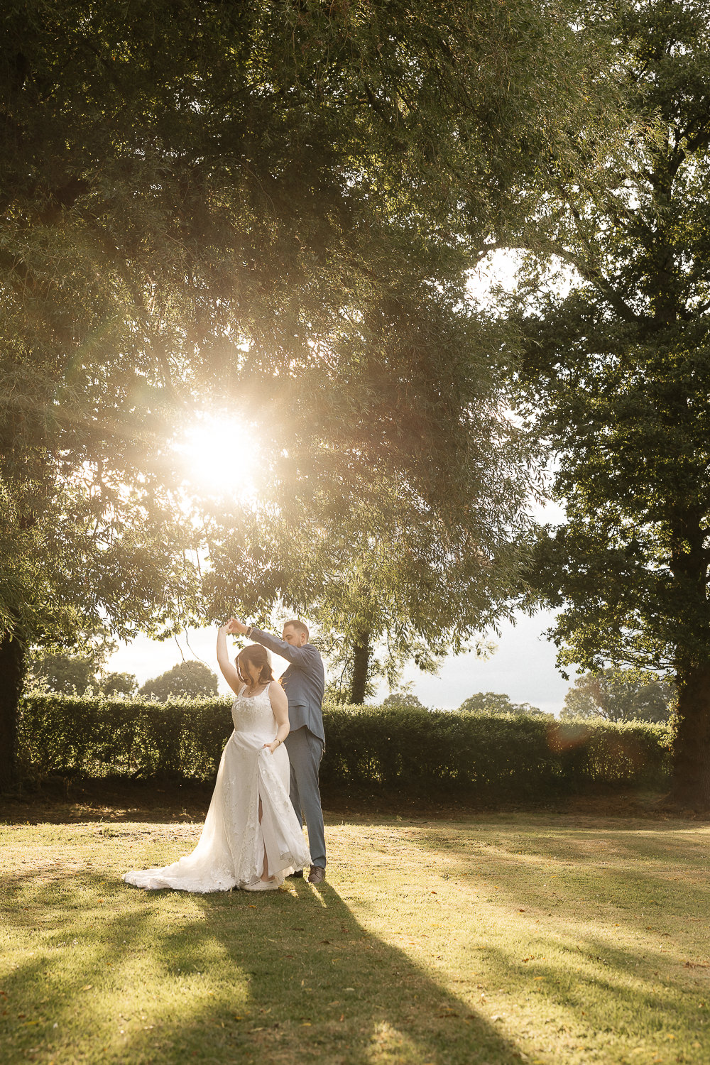Bride and groom dancing under a sunlit tree at Rookery Hall